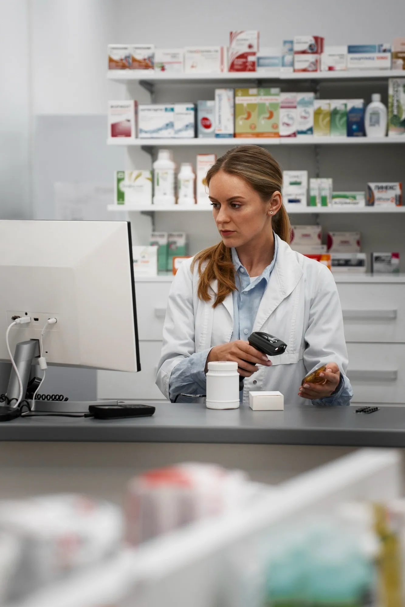 Farmacéutica escaneando una caja de medicamento tras el mostrador